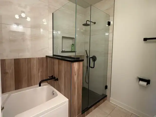 High-rise condo bathroom at The Chandler, Lakeshore East Chicago, with new tub, wood-panel knee wall and frameless glass shower