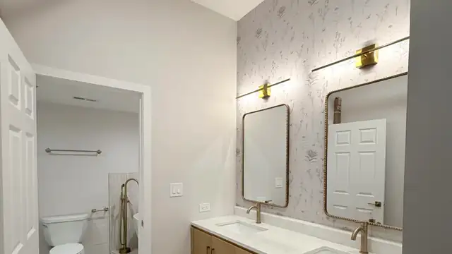 Bathroom renovation at Gotham Lofts, 420 S Clinton, West Loop Chicago, with oak double vanity, brass mirrors and stone top