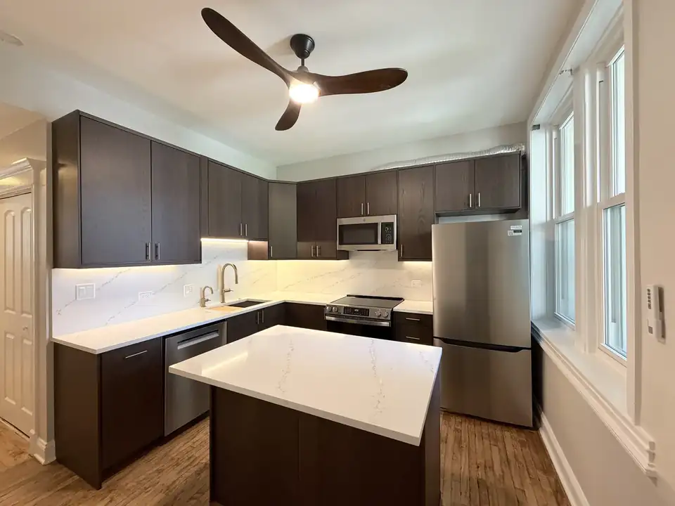Condo remodeling Chicago: Lakeview condo kitchen at 3054 N Sheffield Ave with custom European cabinets, wall of windows and quartz waterfall island