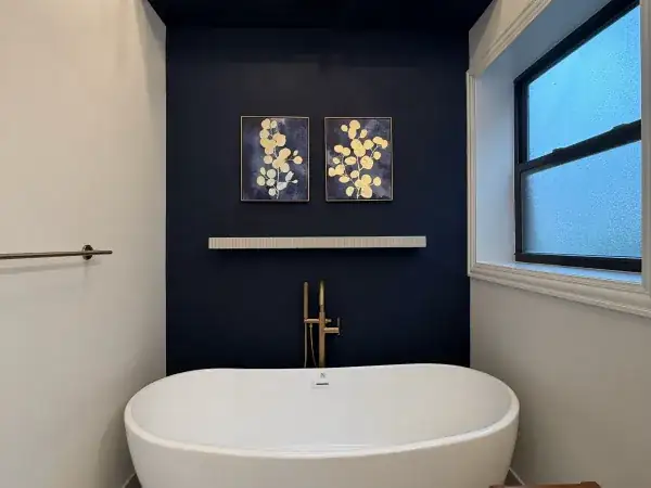 Wicker Park bathroom remodel in Chicago with freestanding tub, navy accent wall and gold fixtures