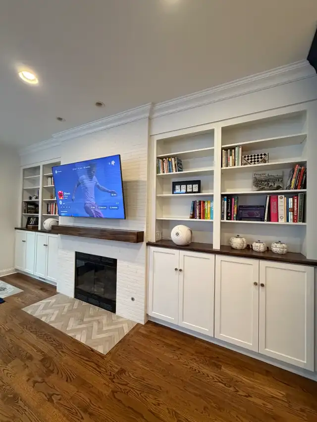 Wicker Park living room with white built-in bookshelves, a wood mantel and a fireplace with herringbone tile